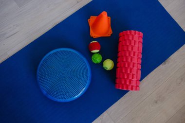 Spor aletli mavi minder, köpük silindir, denge diski, kettlebell ve sabah için hazırlanmış masaj topları.