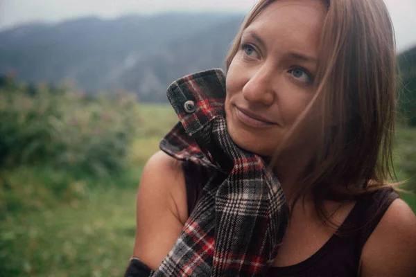 Atkısı yukarı bakan beyaz bir kadın, umut dolu bir ifade, arkasında sisli bir dağ vadisi, bir sonraki yolu planlıyor.