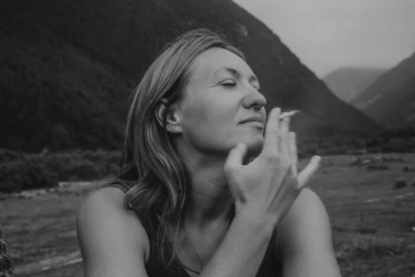 Tek renkli beyaz kadın meditasyonda gözlerini kapatıyor. Yüzüne yakın yumuşak elli sakin bir portre. Gri tonda.