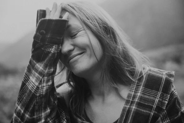 Beyaz kadın gülüyor alnında, tek renkli doğal fon, rahatlama ve neşe ifadesi, samimi.