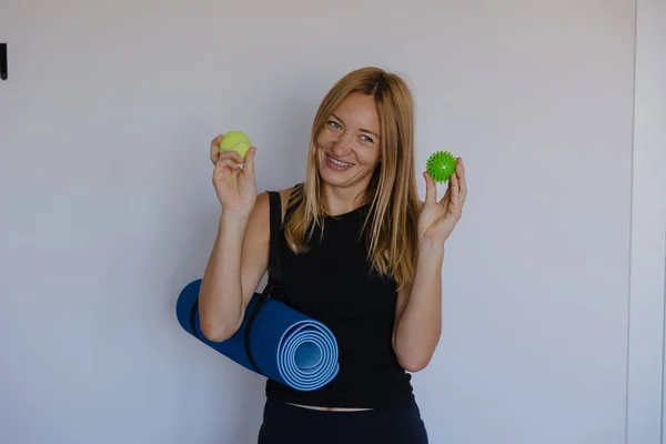 Kafkas terapisti elinde iki tenis topu tutarken gülümsüyor ve mavi paspaslı el gücü öğretiyor.