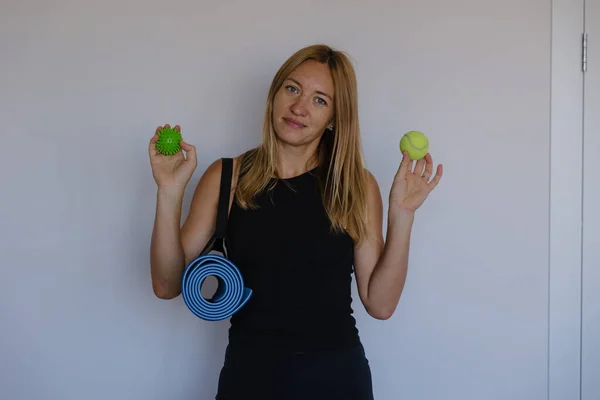 Beyaz tenli koç elinde tenis topu, minder kameraya gülümsüyor el ısınması ve hafif esneme için hazır.