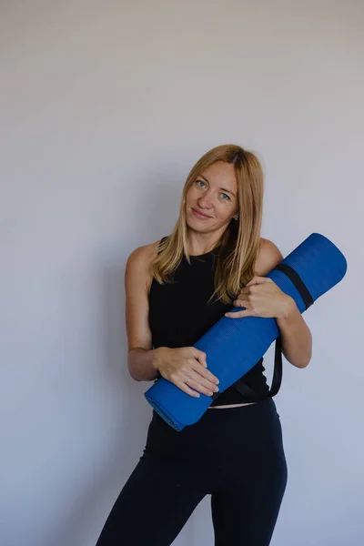 Kafkas pilates eğitmeni elinde mavi minder tutarken hafif gülümseme minder tabanlı günlük antrenman için hazır.