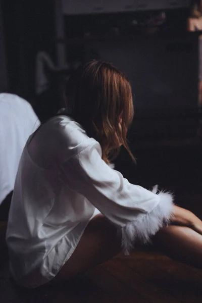 Huysuz yatak odası, alacakaranlık, beyaz kadın. Kürk desenli bornozla sarılmış dizler, ahşap zemin gölgeleri.,