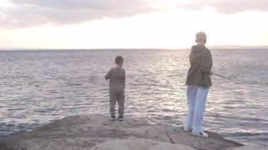 Çocuklar gün batımında deniz kenarında balık tutuyor, İspanya, Alicante