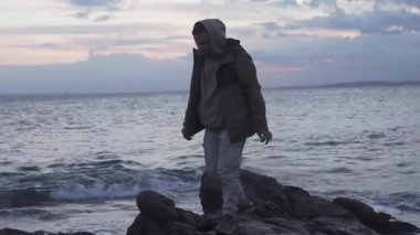 Bir balıkçı sahile bir olta atar deniz kenarındaki kayalıklara ve soğur.,