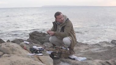 Bir balıkçı deniz kıyısında balık tutmak için teçhizat hazırlar. İspanya, Alykaniye