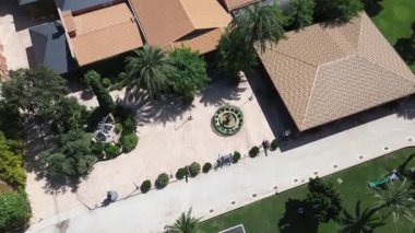 Hava aracı görüntüleri bir şaraphane binasına ve Akdeniz emlak avlusunda yenilenmekte olan bir çeşmeye doğru iniyor. Mimari, bahçeler ve kırsal şaraphaneyi ön plana çıkaran sakin bir genel manzara