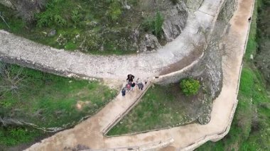 Valencia, İspanya 'daki Bocairent' te hava aracı görüntüleri bir grup turistin kameraya el sallayarak yaya yolunda yürüyüşlerine doğru uçuyor. Çocuklu iki aile ve bir köpek.