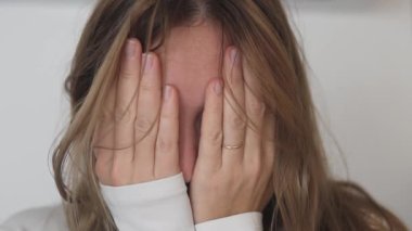 Siyah gözlü bir kadın elleriyle yüzünü kapatıyor.,