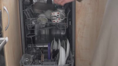 Mutfakta bulaşık yıkayan, tabakları ve bardakları paslanmaz çelik raflara koyan,