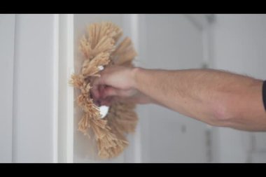 Bir adam duvara yapıştırıcı bant kullanarak dekoratif bir ayna yapıştırıyor ve dikkatlice yerine yapıştırıyor. Basit ev dekorasyonu ve iç dekorasyon kavramı.