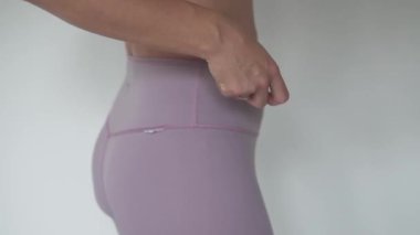 Karnındaki eşofmandan elastik bandı çıkaran ve şişman göbeğini kilolu ve şişman gösteren bir kadın.,
