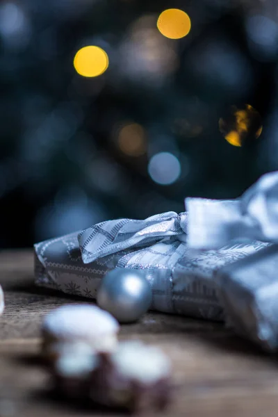 木製のテーブルの上に銀紙や銀電球でクリスマスプレゼント — ストック写真