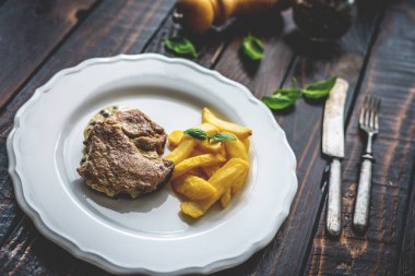 Biber soslu ızgara domuz boynu ve ahşap masada patates kızartması.