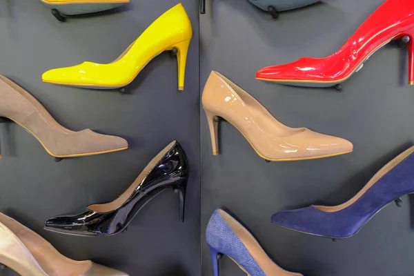 red, yellow, black, brown, blue and beige shoes on heels on store display close-up. Fashion stylish pumps.