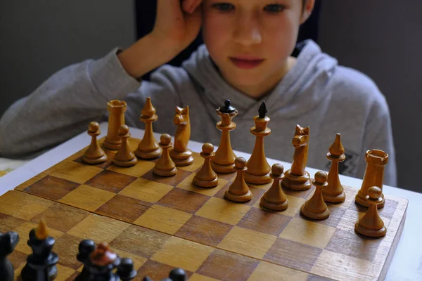 Blonde caucasian boy thinking of a next chess move Playing chess. Strategy, planning concept