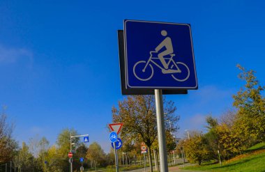 Bisiklet yolu işareti diğer yol işaretleri, ağaçlar ve mavi gökyüzü boyunca. Ulaşım. döngü