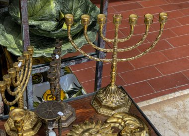 old bronze menorah candlestick across other candelabras close-up on the antique market. Jewish culture, religion