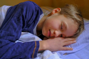  Mavi pijamalı tatlı sarışın çocuk, yakın plan yatakta uyuyor. Çocukların odası..