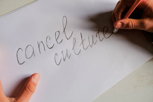 Cancel culture text written on white paper. Person eliminates letters holding a pencil. Cancel culture society concept