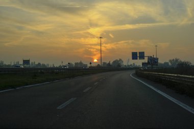 Otobanda gün batımı. Otobanda yol işaretleri var. Ulaşım altyapısı. Taşıma, sürme, seyahat kavramı