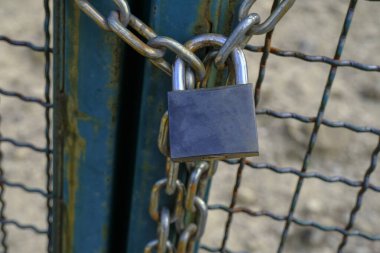 Çitin üzerinde metalik gümüş renkli asma kilit var. Kilit ve zincir