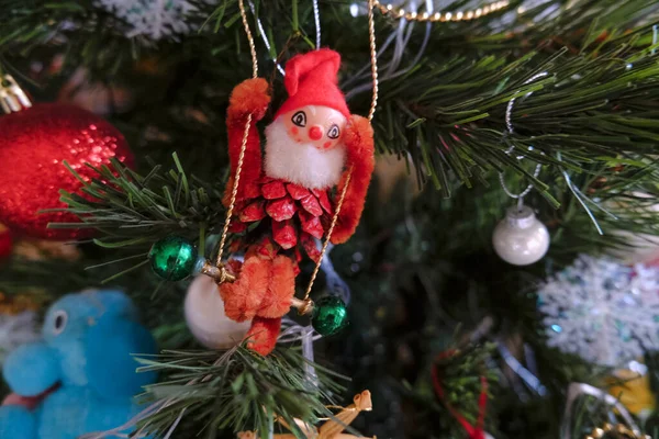 vintage Christmas toy of a dwarf on a swing close-up hanging on Christmas tree across decorations