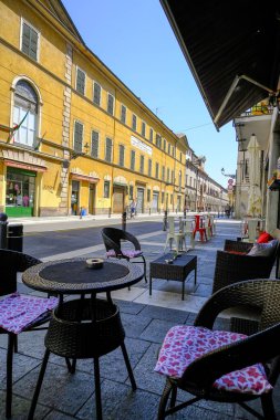 Mayıs 2021 Parma, İtalya: restoran terasında renkli binalarda sandalyeli masalar. Dışarıdaki sokak kafesi. Şehir hayatı