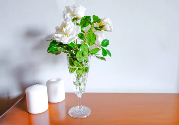 花瓶里有白色的玫瑰 木头上有白色的蜡烛 隔着白色的墙 室内设计 家居装饰 复制空间 — 图库照片