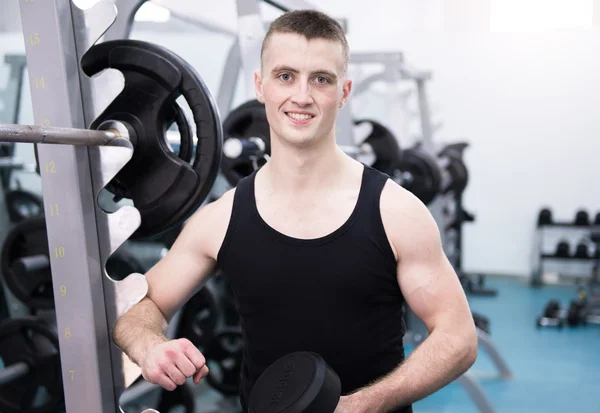 Athletic man with a dumbells in gym — Stock Photo, Image