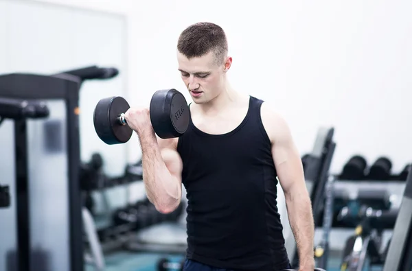 Hombre atlético con mancuernas en el gimnasio —  Fotos de Stock