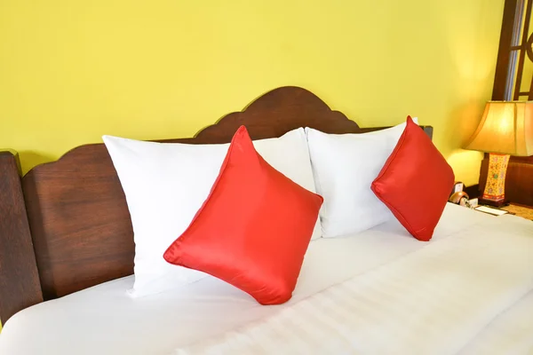 White and red pillows on comfortable bed — Stock Photo, Image
