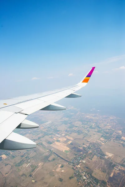 Wing of an airplane flying in the sky over the town — Stock Photo, Image