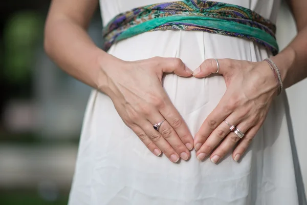 Imagem das mãos da mulher grávida como uma forma de coração na barriga — Fotografia de Stock