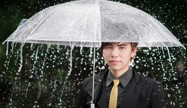 Inteligente hombre de negocios sosteniendo paraguas entre la lluvia — Foto de Stock