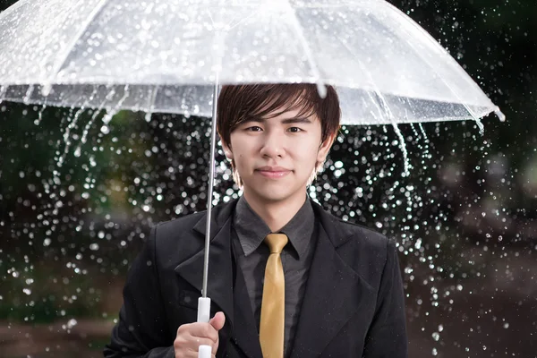 Smart business man holding umbrella among the rain