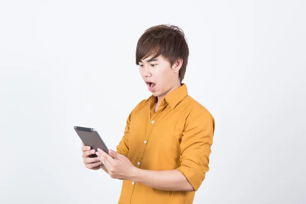 Handsome man in orange shirt playing tablet — Stock Photo, Image