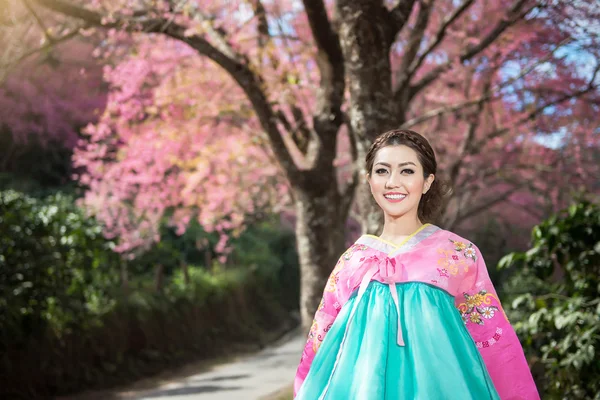 Hanbok: the traditional Korean dress and beautiful Asian girl with sakura — Stockfoto