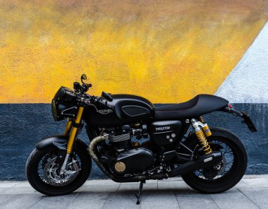 Duvarın yanında siyah klasik bir motosiklet duruyor. 1