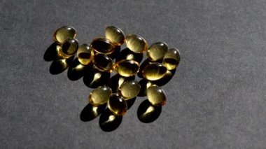 Üzerine D vitamini kapsülleri dökülüyor. Siyah arka plan. Biyolojik olarak aktif katkı maddeleri