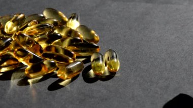 Omega 3 altın balık yağı kapsülleri üzerine dökülür, siyah arkaplan, makro