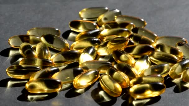 Omega 3 gouden visolie capsules giet op de top, zwarte achtergrond, macro — Stockvideo