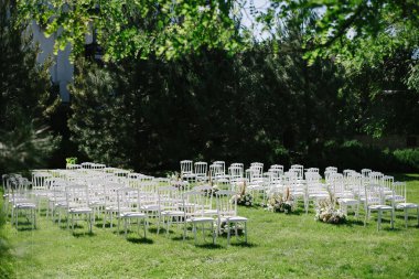 Beyaz sandalyeler düğün töreni için dizildi. çiçek kompozisyonu, dekorasyon