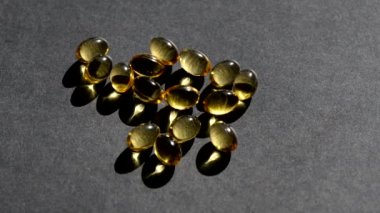 Üzerine D vitamini kapsülleri dökülüyor. Siyah arka plan. Biyolojik olarak aktif katkı maddeleri