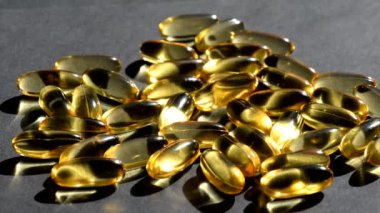Omega 3 altın balık yağı kapsülleri üzerine dökülür, siyah arkaplan, makro