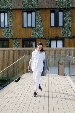 Büyük boy kapüşonlu güzel, güzel bir bayan. Modern manzara ve arkadaki binalar