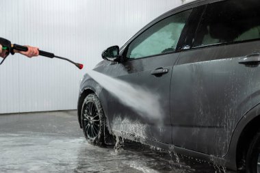 Bir işçi araba yıkama yerindeki aktif köpüğü temizler. Kirli köpük.