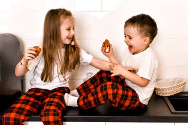 Çocuklar kurabiye yerken mutfakta oynuyorlar.