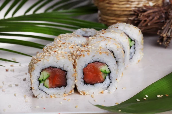 Roll mit Sesam-Sushi-Räucherlachs, Gurken, tropischen Blättern, Stillleben — Stockfoto